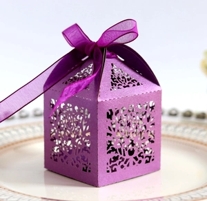 Close-up of laser cut purple candy box with ribbon bow on a decorative white plate