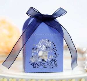 Macro detail of laser-cut hollow house-shaped wedding candy box with a blue ribbon bow