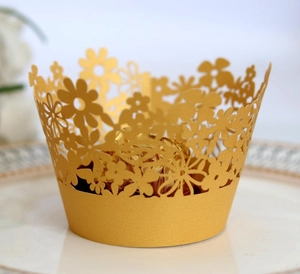 Detail of laser-cut gold lace cupcake wrapper with floral pattern and pearl finish