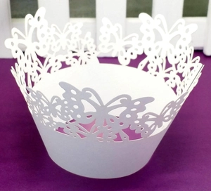 Detailed laser-cut butterfly hollow pattern on white cupcake wrappers for wedding decor