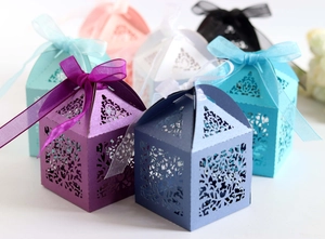Detailed laser-cut pattern on multi-colored favor boxes with elegant organza ribbons
