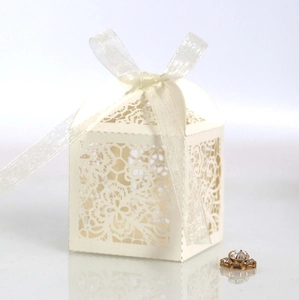 Detail of white laser-cut wedding favor box with floral lace patterns and silk ribbon bow