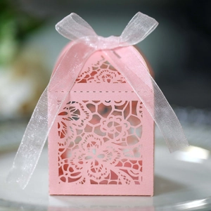 Macro view of pink laser-cut wedding gift box with intricate floral patterns and organza ribbon