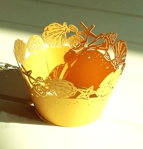 Macro view of laser-cut starfish and seashell patterns on yellow cupcake wrappers