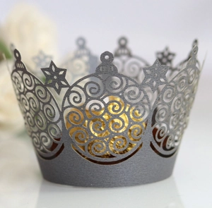Detail of laser-cut silver cupcake wrapper with elegant spiral patterns and gold glitter decor