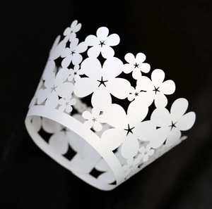 Macro detail of laser-cut floral white cupcake wrappers with shimmering pearl finish