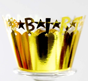 Detail of laser-cut gold foil cupcake wrapper with star patterns and Barty lettering