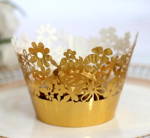 Macro view of gold laser-cut floral cupcake wrappers for wedding party decoration