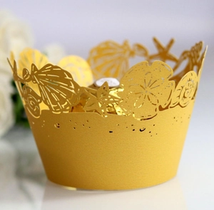 Macro shot of gold laser-cut pearl paper cupcake wrappers with seashell and starfish motifs