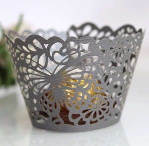 Macro shot of silver pearl laser-cut cupcake wrapper with butterfly and floral patterns