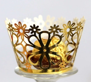 Detail of laser-cut gold floral cupcake wrapper with metallic crown design and chocolate