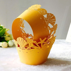 Macro detail of laser-cut yellow paper cake wrapper with sea shell and starfish patterns