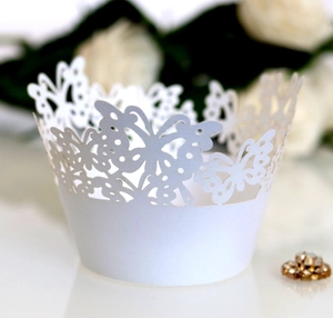 Detailed close-up of white laser-cut butterfly cupcake wrappers for wedding decor