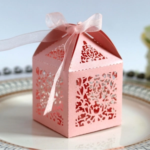 Pink laser-cut wedding candy box with ribbon on a plate for party gift packaging