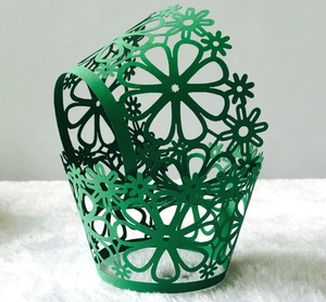 Detailed laser-cut floral pattern on a green hollow cupcake liner for wedding decor