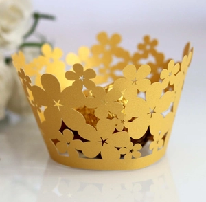 Macro detail of gold flower laser-cut cupcake wrapper with pearl paper metallic finish