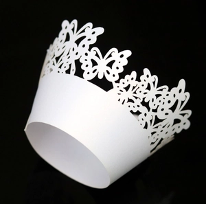 Macro view of laser-cut butterfly patterns on white paper cupcake decorative wrappers