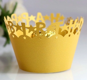 Macro shot of laser-cut Happy Birthday gold cupcake wrappers with star pattern detail