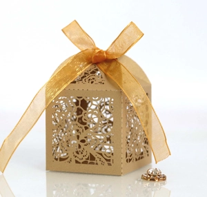 Detail of laser-cut gold wedding favor box with lace pattern and elegant silk ribbon