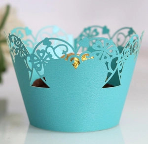 Detailed view of turquoise laser-cut heart pattern cupcake wrapper with gold chocolate