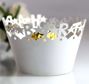 Macro shot of laser-cut Happy Birthday white paper cupcake wrapper with gold foil lining