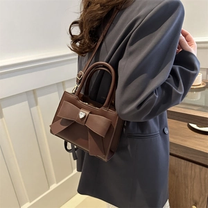 Borsa a tracolla quadrata marrone con fiocco e cristallo a cuore su abito grigio