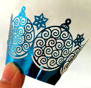 Close-up of laser-cut blue mirror cupcake wrapper featuring snowflake and swirl patterns