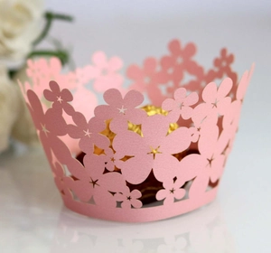 Pink laser-cut floral cupcake wrappers with intricate hollow design for wedding decor