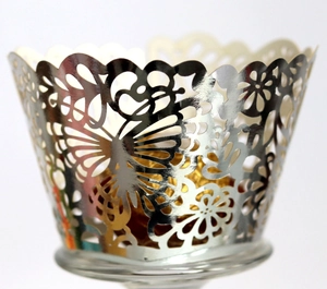 Detail of silver laser-cut cupcake wrapper with hollow butterfly and floral patterns