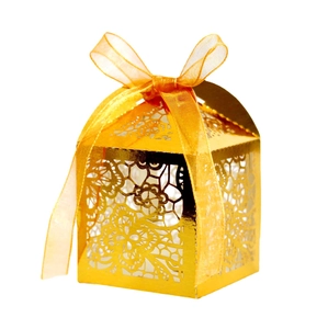 Detailed laser-cut hollow rose pattern on a shiny gold wedding candy box with a ribbon