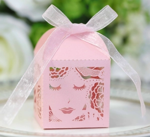 Détail d'une boîte cadeau rose découpée au laser avec motifs floraux et ruban en mousseline
