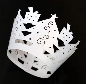 Close-up of white paper crown featuring intricate laser-cut star and wavy patterns
