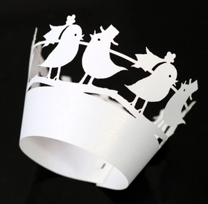 Macro detail of laser-cut pearl white cupcake wrapper with elegant bird silhouette