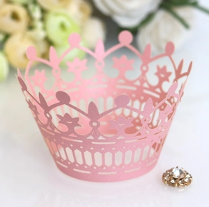 Detail of pink laser-cut crown cupcake wrapper featuring a gold rhinestone accent