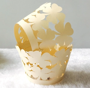 Laser-cut four-leaf clover hollow cupcake wrappers in cream yellow paper with handle