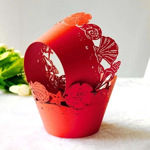 Macro shot of red laser-cut cupcake wrappers with ocean shell and starfish patterns