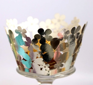 Macro detail of laser-cut floral cupcake wrappers with silver metallic glossy finish