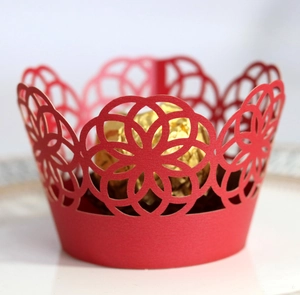 Detail of red laser-cut cupcake wrappers with geometric hollow pattern for wedding decor