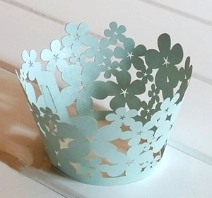 Close-up of laser-cut cupcake wrappers with mint blue floral patterns for wedding decor
