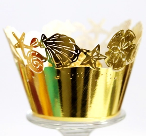Close-up of golden mirror cupcake wrapper with laser-cut ocean starfish and seashell design