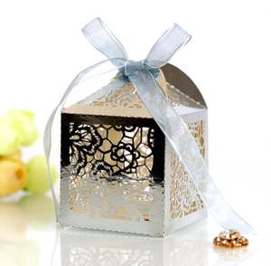 Detail of silver laser-cut wedding favor box with blue organza ribbon and floral pattern