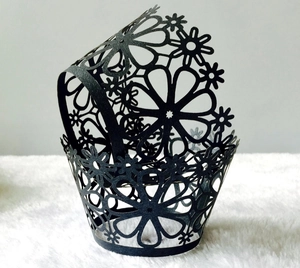 Detail view of laser-cut black paper cupcake liners with intricate floral patterns