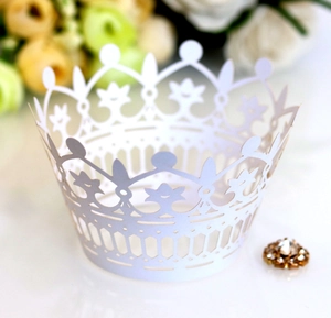 Close-up of white laser-cut crown cupcake wrappers with elegant hollow patterns