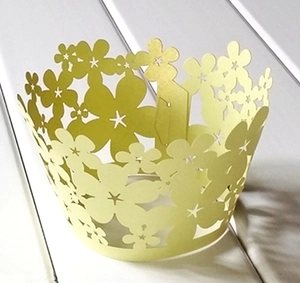 Close-up of yellow laser-cut cupcake wrapper with intricate floral hollow design