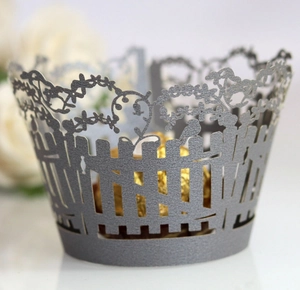 Detail of laser-cut grey cupcake wrapper with floral fence and bird silhouette design