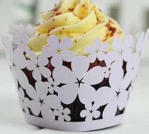 Close-up of white laser-cut floral cupcake wrappers with intricate hollow patterns