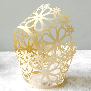 Detailed laser-cut floral pattern on pearlescent paper cupcake wrappers for weddings