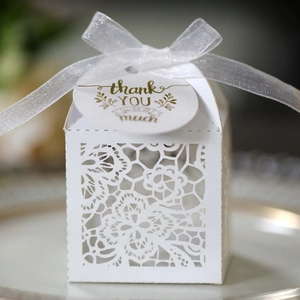 Detail of white laser-cut wedding favor box with ribbon and gold Thank You tag