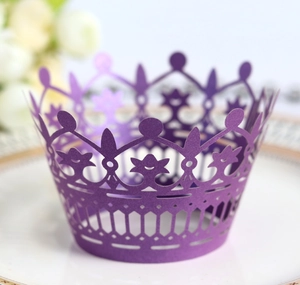Elegant purple laser cut crown cupcake wrapper displayed on a ceramic plate