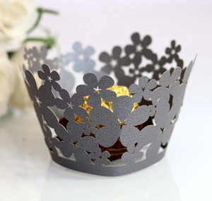 Macro detail of laser-cut pearl paper cupcake liners with delicate floral patterns